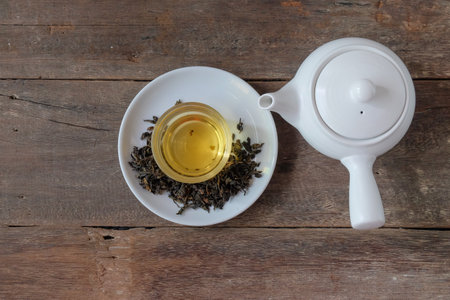 White Tea pot and cups of hot beverage on wooden.
