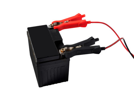 A motorcycle battery, charging with red and black cables.の写真素材