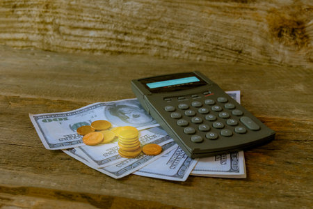 Calculator on US money and coins on table.