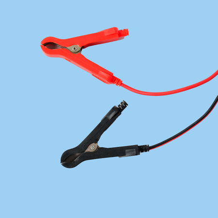 Red and black car battery jumper cables on background.