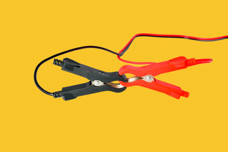 Red and black car battery jumper cables on background.