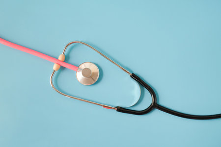 Pink stethoscope in black stethoscope on background.