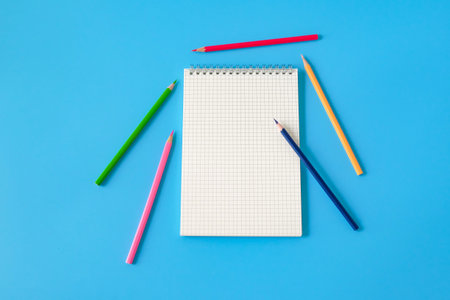 Top view of notebook and color pencil on background.