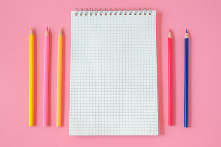 Top view of notebook and color pencil on background.