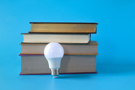 Light bulb and hard cover books on background.の写真素材