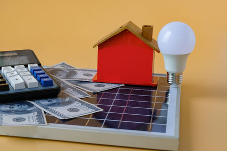 Composition with solar panel, led lamp, money and model house on texture background.