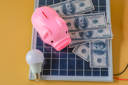 Composition with solar panel, led lamp, money and piggy bank on texture background.の写真素材