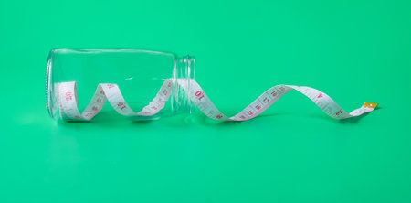 Health concept. Measuring tape in bottle on color background.の写真素材
