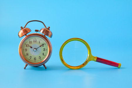 Alarm clock and Magnifying glass on background.