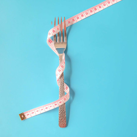 Fork with Measuring tape around on background.の写真素材