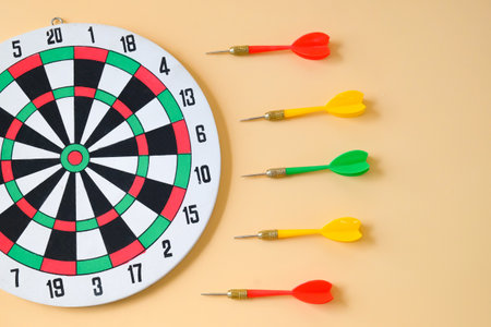 A dartboard with green and red darts rests on background.