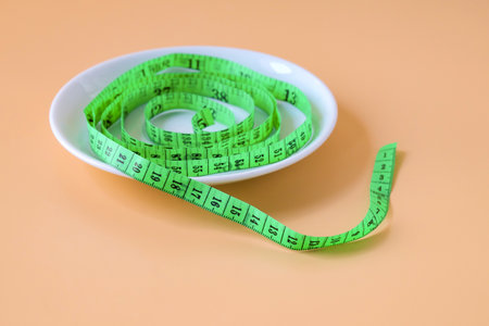 Green measuring tape on white plate.の写真素材