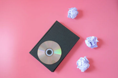Compact disc on old book with crumpled sheets.