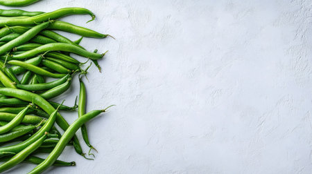 Top view of vibrant green beans arranged neatly on a white surface, with plenty of space for copy.の素材