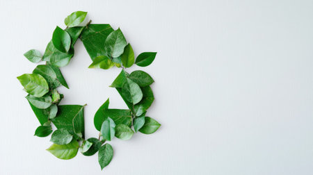 Green leaves forming a recycling symbol on a light background, promoting eco-friendliness. Copy space.の素材