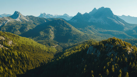 Aerial perspective of a mountain range with a dense forest, clear sky area for textの素材