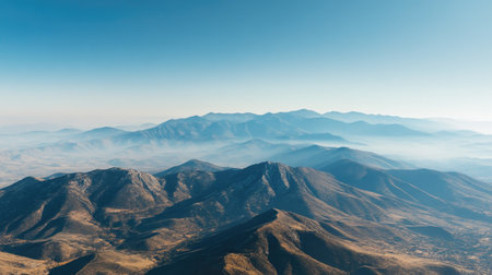 Aerial view of a majestic mountain range with a clear blue sky above and ample space for text on the horizonの素材