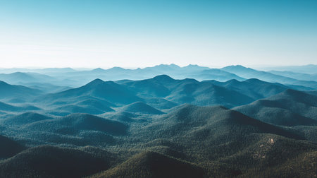 Aerial view of a majestic mountain range with a clear blue sky above and ample space for text on the horizonの素材