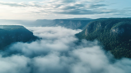 Aerial shot of a mountain landscape with misty clouds, open sky area for textの素材
