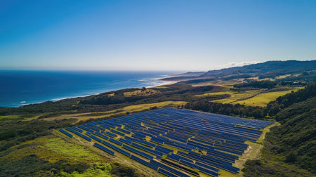 Bird's eye view of a solar farm near the coast, with the ocean in the background, and copy space in the sky.の素材