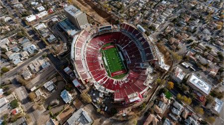 This aerial shot captures an empty stadium nestled within a vibrant urban landscape, showcasing its architectural design, seating arrangement, and surrounding residential area.の素材