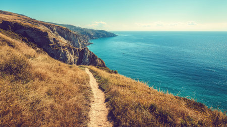 Lonely hiking trail along a coastal cliff, space for text in the wide-open ocean view.の素材