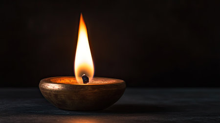 Traditional Jain deepak with a soft flame, no people, dark background, ample copy spaceの素材