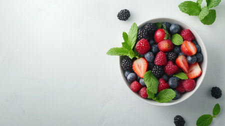 A bowl of mixed berries and mint leaves, perfect for summer snacks, with ample text spaceの素材