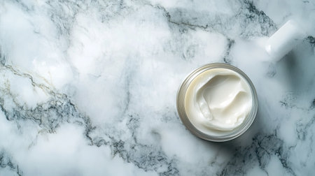 A top view of a creamy skincare product in an elegant jar displayed on a beautiful marble surface, perfect for enhancing beauty and wellness imagery in marketing materials.の素材