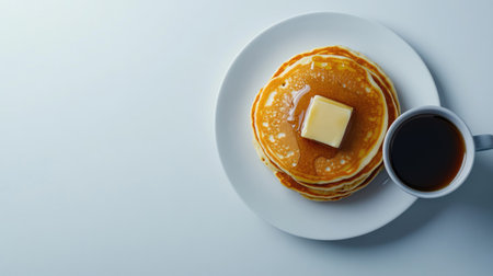 A mouth-watering plate of pancakes topped with butter and served with a cup of coffee, perfect for a delicious breakfast or brunch experience.の素材