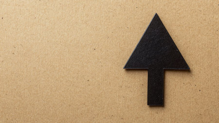 A black arrow symbol designed in a minimalist style against a brown textured background, ideal for conveying direction, guidance, and progress in creative projects.の素材