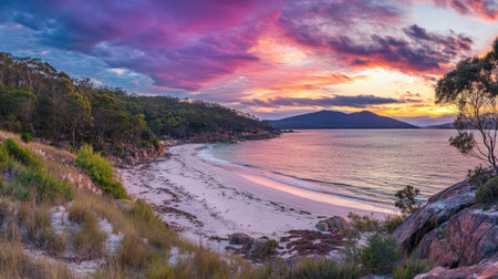 A breathtaking sunset casts colorful reflections over calm waters, highlighting the lush greenery and rocky shoreline in a peaceful coastal setting perfect for relaxation.の素材