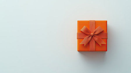 A vibrant orange gift box adorned with a decorative ribbon sits elegantly against a soft background, perfect for conveying joy and celebration during special occasions.の素材