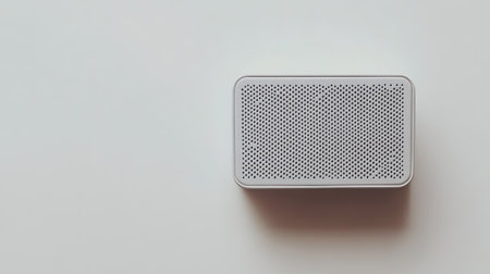 A sleek, compact portable speaker displayed on a white surface offers a modern design that enhances any space, perfect for music enjoyment and audio solutions.の素材