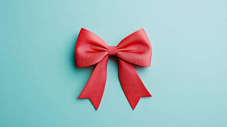 A striking red bow with long tails rests elegantly on a soft blue background, ideal for adding a touch of charm to gifts, decorations, and festive occasions.の素材