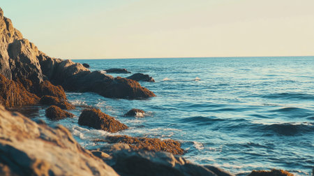A stunning seascape depicting tranquil waters lapping against rocky shores, illuminated by the soft glow of early morning light. Perfect for nature lovers.の素材