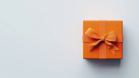 A vibrant orange gift box adorned with a matching ribbon set against a light background, ideal for representing joy, celebration, and special moments in various festivities.の素材