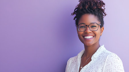 A cheerful woman with glasses smiles brightly against a soft purple background, exuding confidence and joy. Her natural hairstyle and casual outfit add to the warm, friendly vibe.の素材