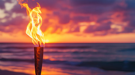 Golden flames of a beachside torch flicker against the backdrop of an orange-pink sunset skyの素材
