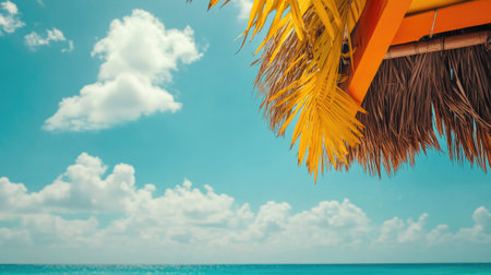 Enjoy a peaceful beach scene featuring a thatch umbrella, gentle ocean waves, and a vibrant blue sky adorned with fluffy clouds, inviting relaxation.の素材