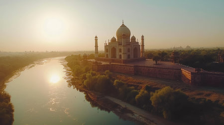 Experience the mesmerizing beauty of the Taj Mahal at sunrise, reflected in the serene river, showcasing its stunning architecture amidst tranquil nature.の素材