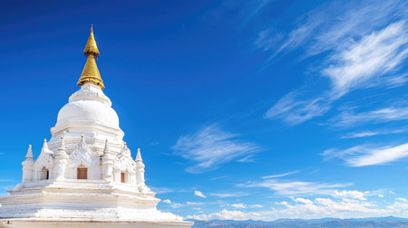 A stunning white stupa with a golden spire stands against a vibrant blue sky, surrounded by tranquil landscapes, symbolizing peace and spirituality in architecture.の素材
