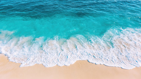 A stunning aerial view of clear ocean waves gently wash onto a sandy beach, showcasing vibrant blue waters and a serene shoreline perfect for relaxation and escape.の素材