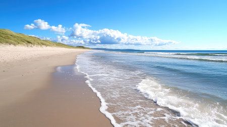 A serene beach scene featuring gentle waves lapping at the shore under a clear blue sky, surrounded by lush greenery and distant clouds, ideal for relaxation.の素材