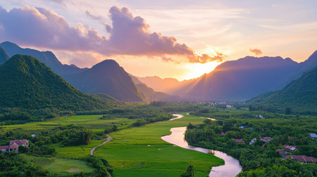 A breathtaking view captures the tranquil moment of sunset over a lush green valley, surrounded by majestic mountains and meandering river.の素材