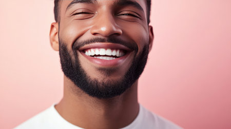 A joyful young man displays a radiant smile against a soft pink background, capturing the essence of happiness and positivity in a simple portrait.の素材