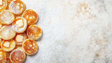 A delightful arrangement of golden pancakes topped with butter, dusted with sugar, sitting on a textured background. Perfect for breakfast or dessert.の素材