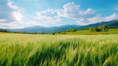 Vibrant landscape featuring a lush green field with majestic mountains in the background under a bright blue sky adorned with fluffy clouds. Perfect for nature enthusiasts.の素材
