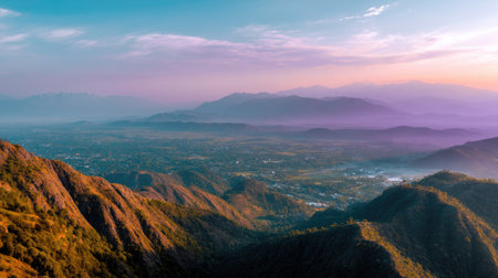 Captivating view of a mountain landscape at sunrise, showcasing gentle hues and soft mist embracing the valley below and majestic peaks in the distance.の素材