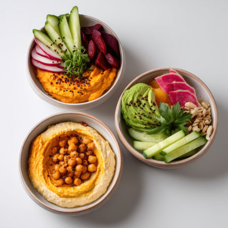 Beautifully arranged bowls of fresh vegan dips featuring hummus and vibrant vegetables. Perfect for healthy snacking or entertaining guests.の素材